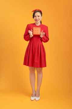 快乐年轻的亚洲女人持有礼物盒子孤立的橙色背景