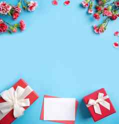 母亲的一天礼物设计概念假期问候卡红色的康乃馨花束明亮的蓝色的表格背景