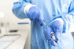 概念全球疫苗接种战斗科维德流感大流行医疗健康工人完整的保护工具包蓝色的手套准备药物注射画疫苗剂量瓶注射器