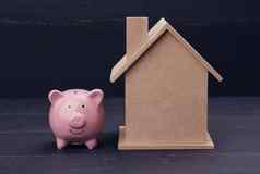 粉红色的陶瓷小猪银行房子蓝色的背景真正的房地产租赁购买出售概念