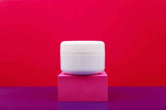 白色光滑的化妆品Jar粉红色的基座红色的紫色的背景复制空间