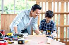 亚洲父亲小心翼翼地儿子木材工作场所木工快乐情感亚洲家庭概念保持首页享受好的关系爱好