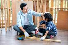 亚洲父亲触摸头儿子钻木材首页工作场所木工快乐情感亚洲家庭概念保持首页享受好的关系爱好
