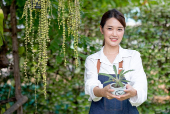 美丽的亚洲女孩持有能植物现在相机站前面绿色墙房子可持续发展的成长仙人掌植物概念