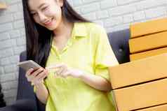 年轻的亚洲女人企业家检查订单智能手机客户购买在线物流交付在线购物女卖方业务锻造商人电话