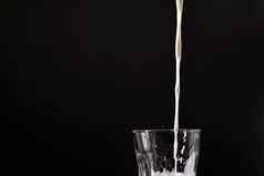 倒牛奶玻璃飞溅白色液体孤立的黑暗背景