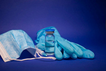 疫苗瓶小玻璃瓶标签医疗注射器注射针蓝色的医疗面具手套孤立的蓝色的背景治愈发展冠状病毒疫苗新冠病毒