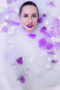 模型女孩紫罗兰色的化妆牛奶浴紫罗兰色的花