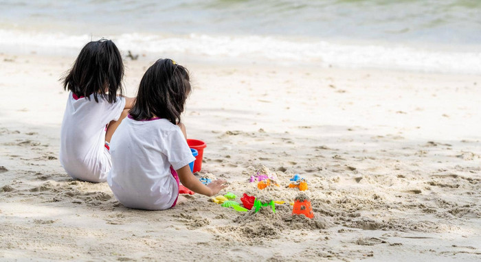 双胞胎女孩玩海滩玩具坐着海滩沙子白色沙子