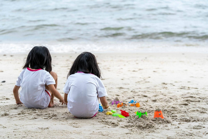 双胞胎女孩玩海滩玩具坐着海滩沙子白色沙子