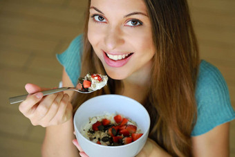 关闭美丽的年轻的女人微笑吃斯凯尔麦片牛奶什锦早餐水果种子首页焦点模型眼睛室内图片健康的食物概念