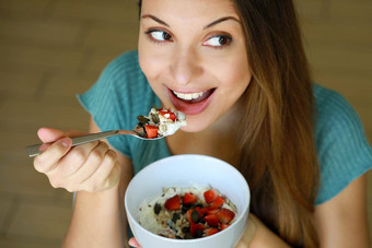 关闭视图美丽的年轻的女人吃斯凯尔酸奶草莓麦片牛奶什锦早餐种子首页一边焦点模型眼睛室内图片健康的食物概念