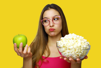 女人选择不健康的碗流行玉米健康的绿色苹果怀疑健康的食物伤心吃苹果