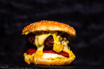 细节新鲜的美味的牛肉芝士汉堡融化了奶酪孤立的黑色的背景