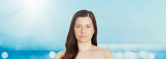 护肤品太阳保护夏天肖像美丽的年轻的晒黑了女人蓝色的海天空背景美健康旅行概念