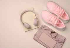 一对粉红色的运动鞋无线耳机智能手机聪明的看粉红色的背景