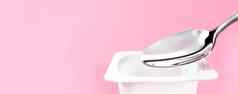 酸奶杯银勺子粉红色的背景白色塑料容器酸奶奶油新鲜的乳制品产品健康的饮食营养平衡