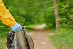 志愿者清洁垃圾公园人护理地球污染塑料垃圾工人手持有垃圾袋志愿者手选择塑料垃圾草公园生态友好的背景森林