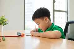可爱的微笑男孩家庭作业着色页面写作绘画孩子们油漆孩子们画学龄前儿童书图书馆色彩斑斓的铅笔纸桌子上有创意的男孩