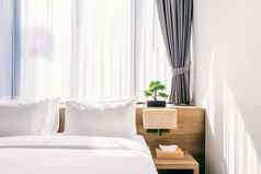 特写镜头白色枕头床上装饰光灯绿色树花盆酒店卧室室内