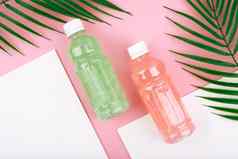 有创意的平躺瓶粉红色的绿色排毒饮料粉红色的白色背景棕榈叶子