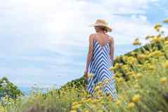 年轻的女人穿条纹夏天衣服稻草他站超级布鲁姆野花放松enjoing美丽的自然亚得里亚海海沿海自然克罗地亚