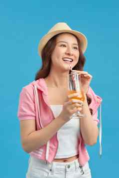快乐亚洲女人夏天休闲衣服玻璃新鲜的水果汁喝蓝色的背景