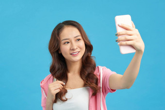 亚洲女人采取自拍智能手机孤立的蓝色的背景