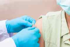 医生男人。注射冠状病毒疫苗年轻的女人肩膀橡胶保护手套把胶粘剂绷带石膏