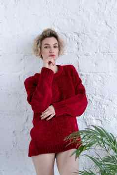 年轻的美丽的女人摆姿势红色的毛衣工作室