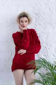 年轻的美丽的女人摆姿势红色的毛衣工作室