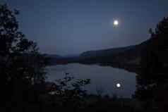 月光发光的满月反映了湖午夜山树