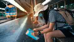 正常的旅行者概念年轻的女旅游穿面具旅游地图等待火车火车站