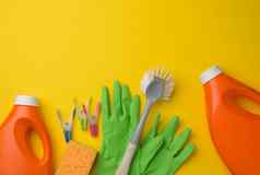 橡胶绿色手套清洁橙色塑料瓶洗涤剂刷黄色的背景集