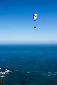 滑翔伞飞行前面蓝色的天空蓝色的水