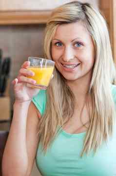 热情的女人喝橙色汁厨房