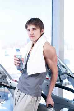 男人。健身房锻炼运行机喝水
