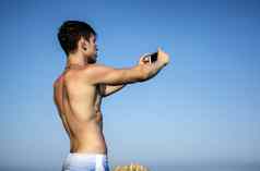赤膊上阵年轻的男人。采取自拍照片海滩