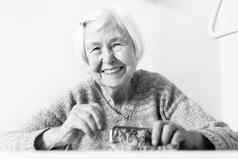 快乐的上了年纪的年女人坐着表格首页快乐养老金储蓄钱包支付账单黑色的白色