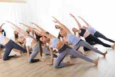 集团年轻的运动有吸引力的人瑜伽工作室练习瑜伽教训教练伸展运动地板上trikonosana三角形瑜伽构成健康的活跃的生活方式工作健身房