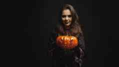 年轻的女人穿着女巫持有pumpking