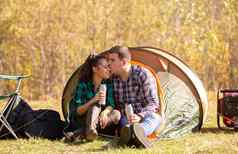 年轻的夫妇爱热水瓶手接吻前面帐篷