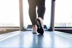 关闭女脚穿运动鞋运行跑步机健身健身房饮食生活方式重量损失胃肌肉健康的概念