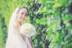 美丽的年轻的女人婚礼一天白色衣服树