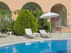 空酒店游泳池阳光明媚的一天夏天假期视图蓝色的水池白色日光浴浴床伞绿色手掌希腊科孚岛岛