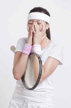 年轻的女网球球员手脸白色背景