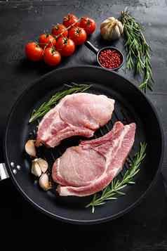 猪肉肚子农场新鲜的肉片石油香料烧烤成分烹饪黑色的长柄平底煎锅黑暗黑色的板岩背景