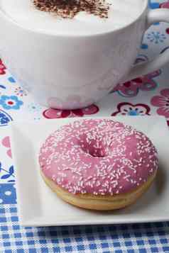 粉红色的甜甜圈杯卡布奇诺咖啡