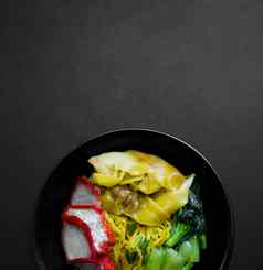 蛋面条馄饨红色的烤猪肉绿色蔬菜黑色的背景