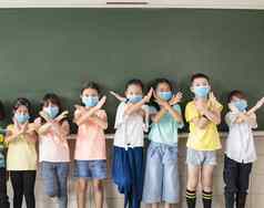 集团多样化的年轻的学生穿面具显示停止标志手势教室